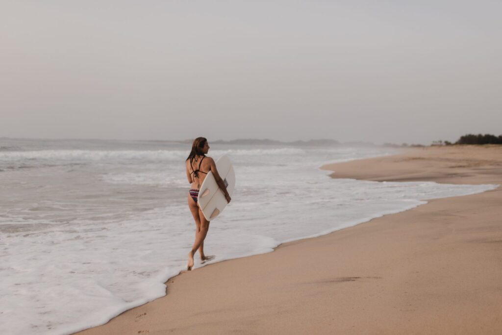 Surferin mit Surfbrett am Strand von Arugam Bay